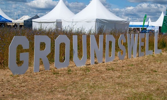 A Groundswell sign in a field with marquees behind.